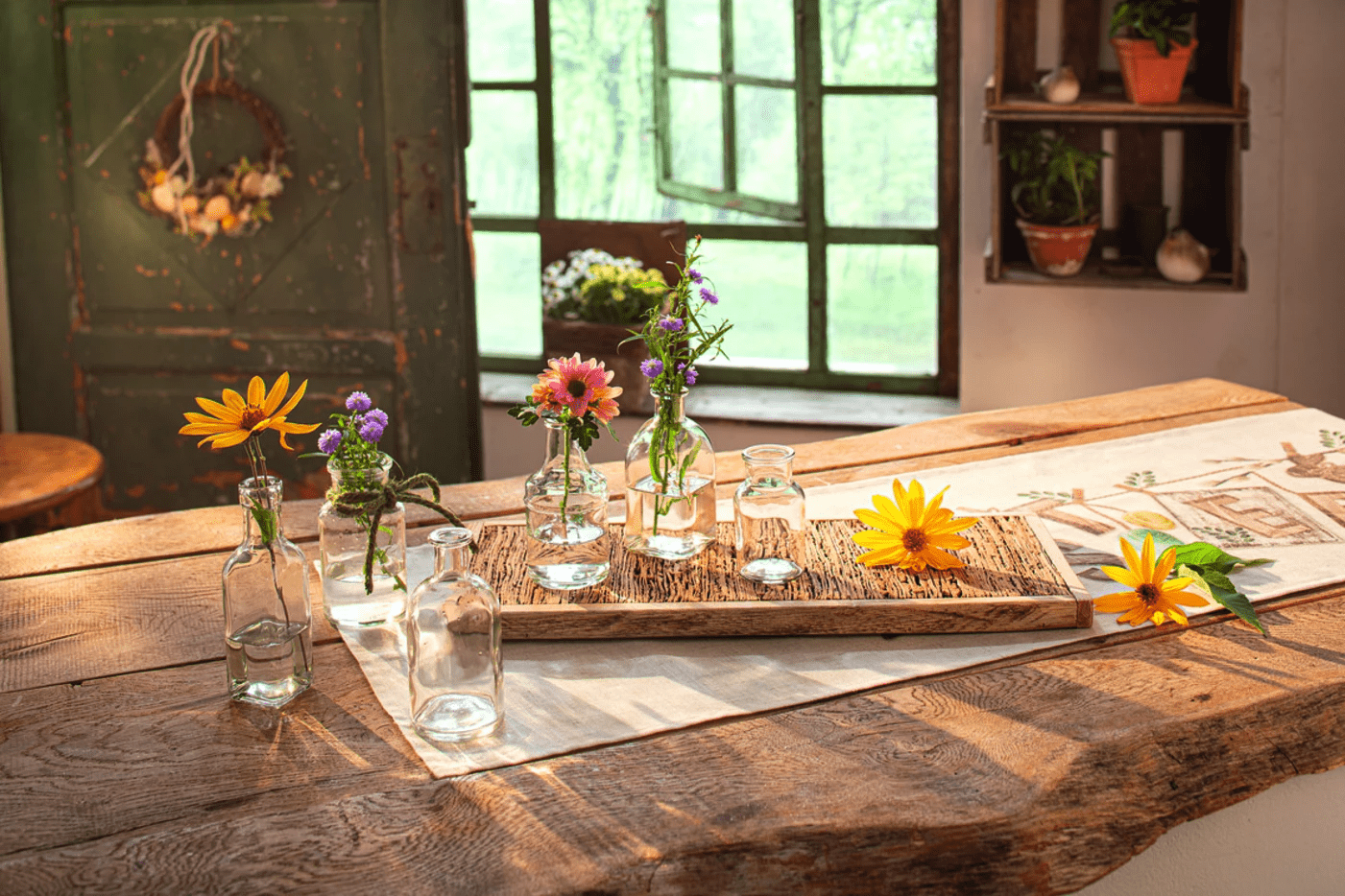 Frühlingsdeko 2025: Arrangement von frischen Frühlingsblumen in kleinen Glasvasen auf rustikalem Holztisch